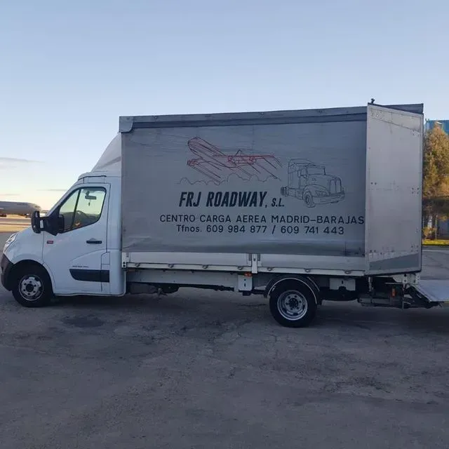 Un camión blanco está estacionado en un estacionamiento con un cartel que dice frj roadway sl