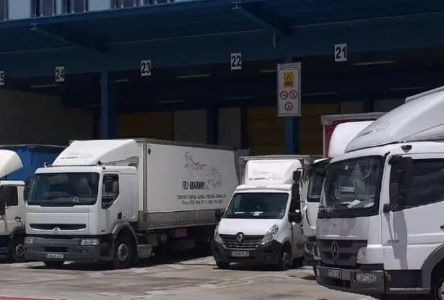 Una fila de camiones blancos están estacionados frente a un edificio