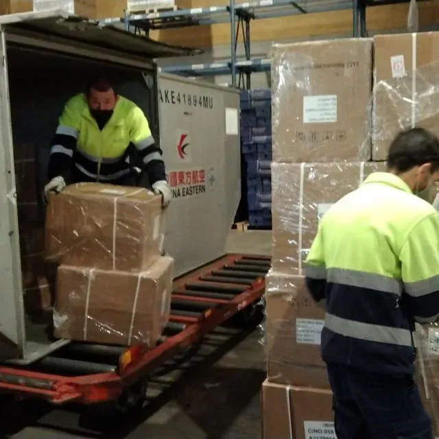 Un hombre con una chaqueta amarilla está cargando cajas en un camión que dice