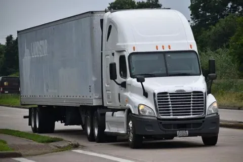 Un camión semirremolque blanco circula por una calle.
