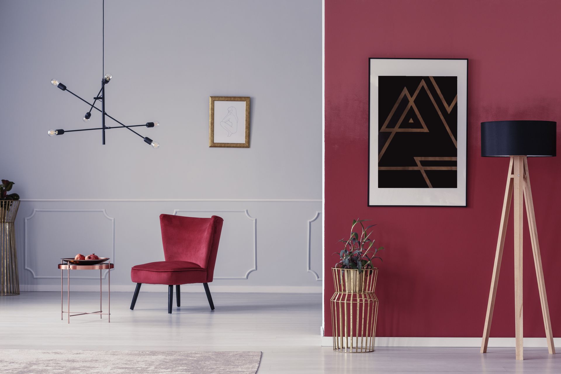 Salon avec murs rouges et gris, chaise en velours rouge, art abstrait et éclairage moderne.