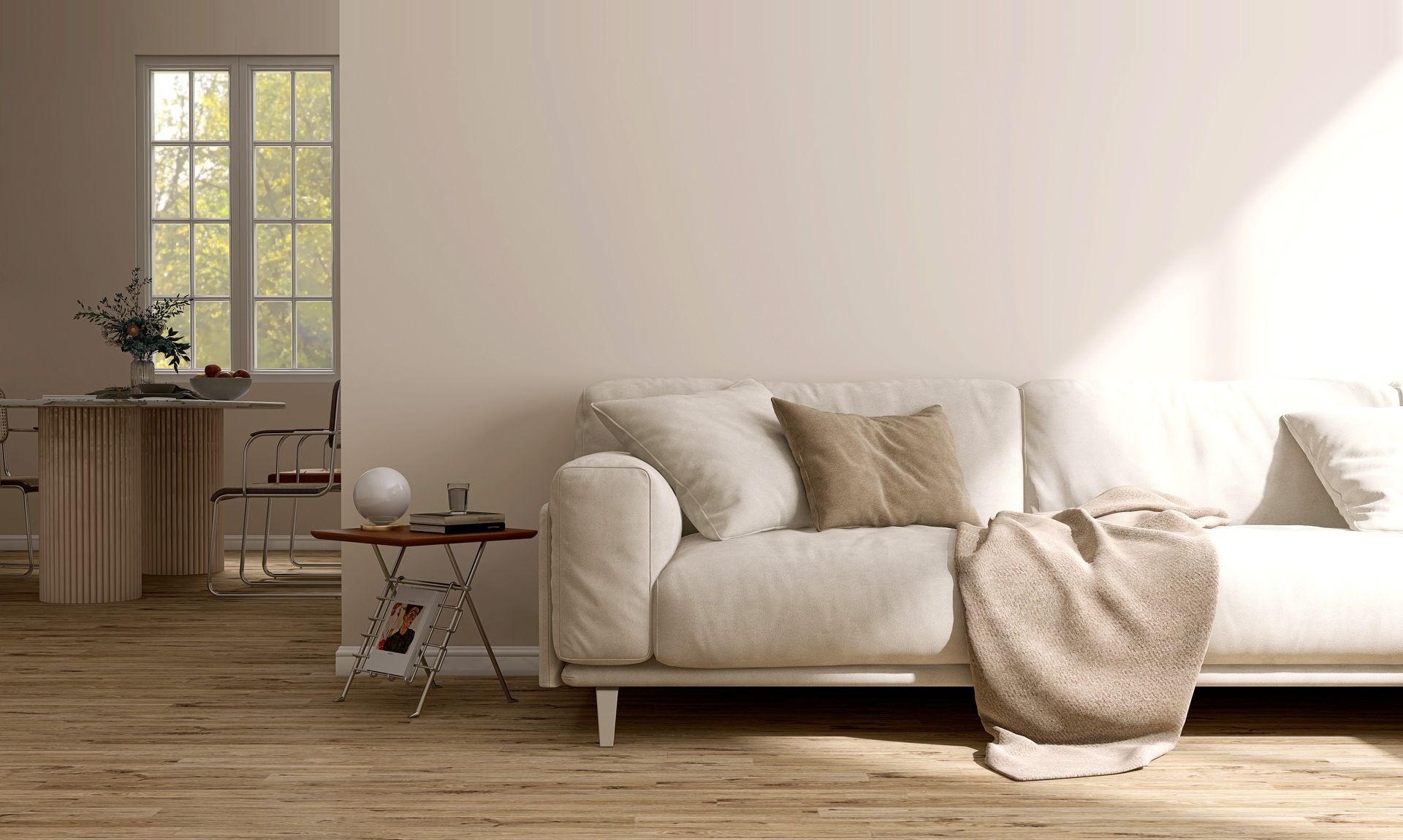 Salon aux tons neutres avec un canapé crème, une petite table d'appoint et une fenêtre donnant sur une zone bordée d'arbres.