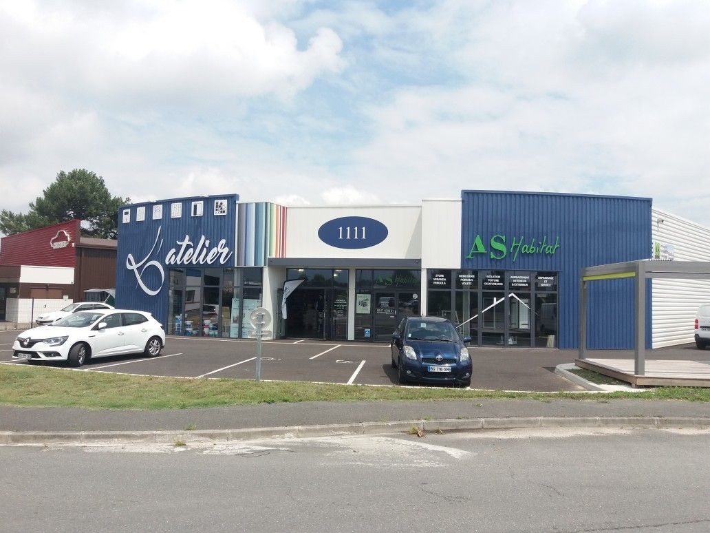 Façade de concessionnaire automobile avec voitures garées, façade bleue et blanche, ciel nuageux
