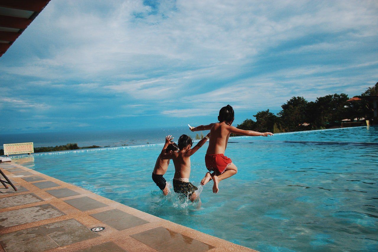 Trois enfants plongeant dans une piscine