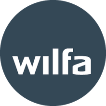 Wilfan logo valkoisilla pienaakkosilla tummansinisellä pyöreällä taustalla