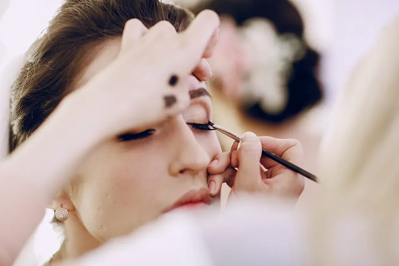 Una mujer se está maquillando con un maquillador.