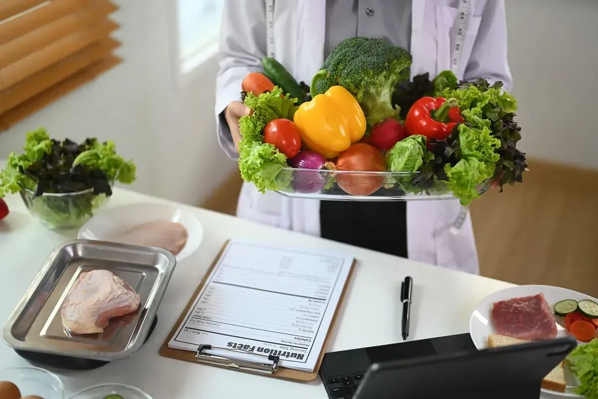 Un nutricionista sostiene una bandeja de frutas y verduras.