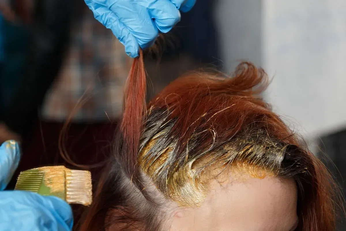Una mujer se está tiñendo el pelo en la peluquería.