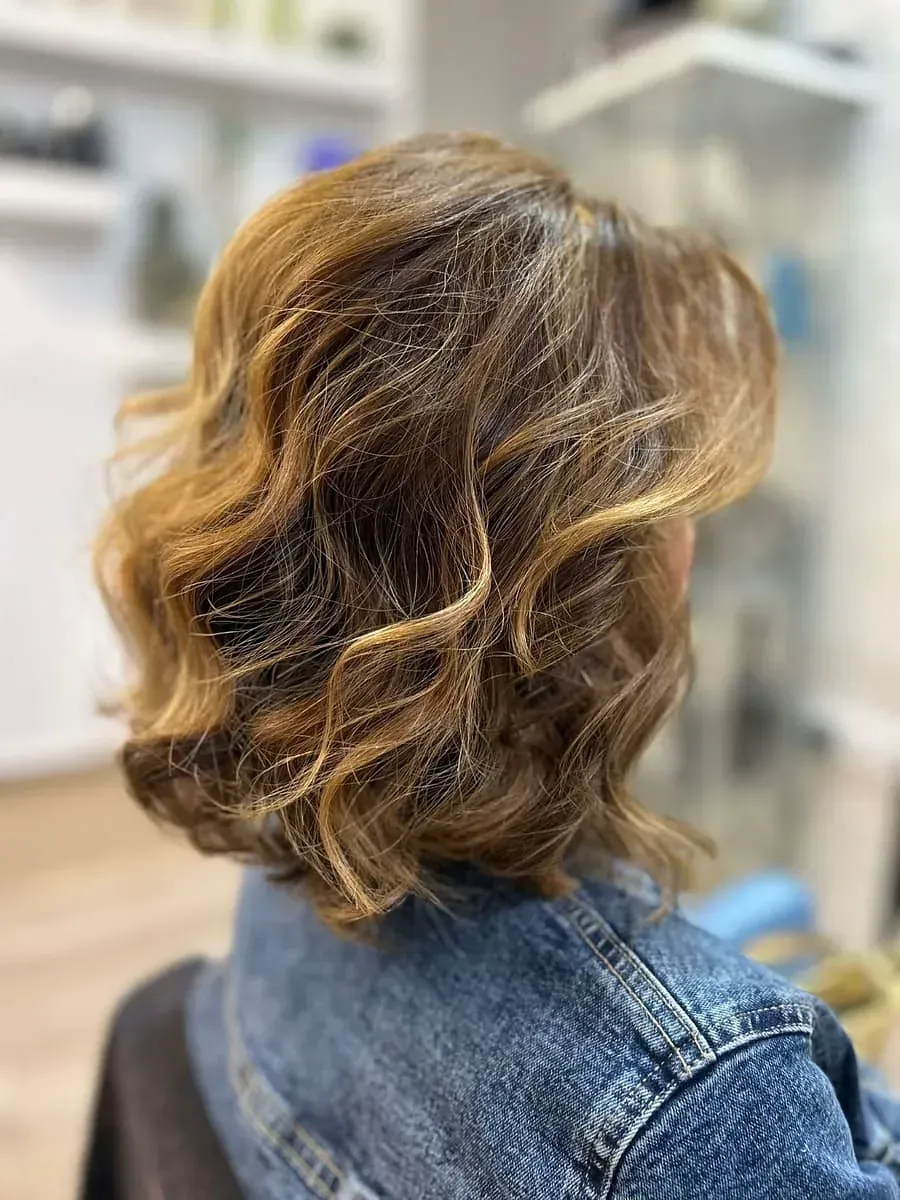 Una mujer con cabello corto y ondulado lleva una chaqueta vaquera.