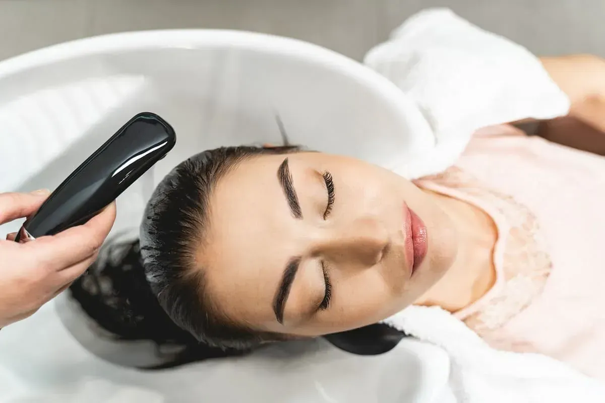 Una mujer se lava el cabello en un lavabo de una peluquería.
