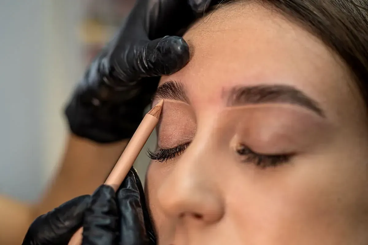 Una mujer se hace dibujar las cejas con un maquillador.