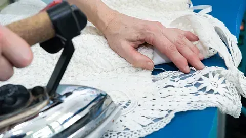 Una persona está planchando un trozo de encaje sobre una mesa.