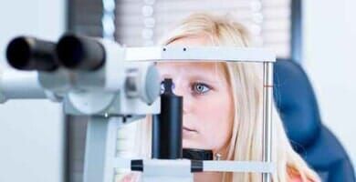 Mulher sendo submetida a exame oftalmológico com biomicroscópio de lâmpada de fenda em consultório médico.