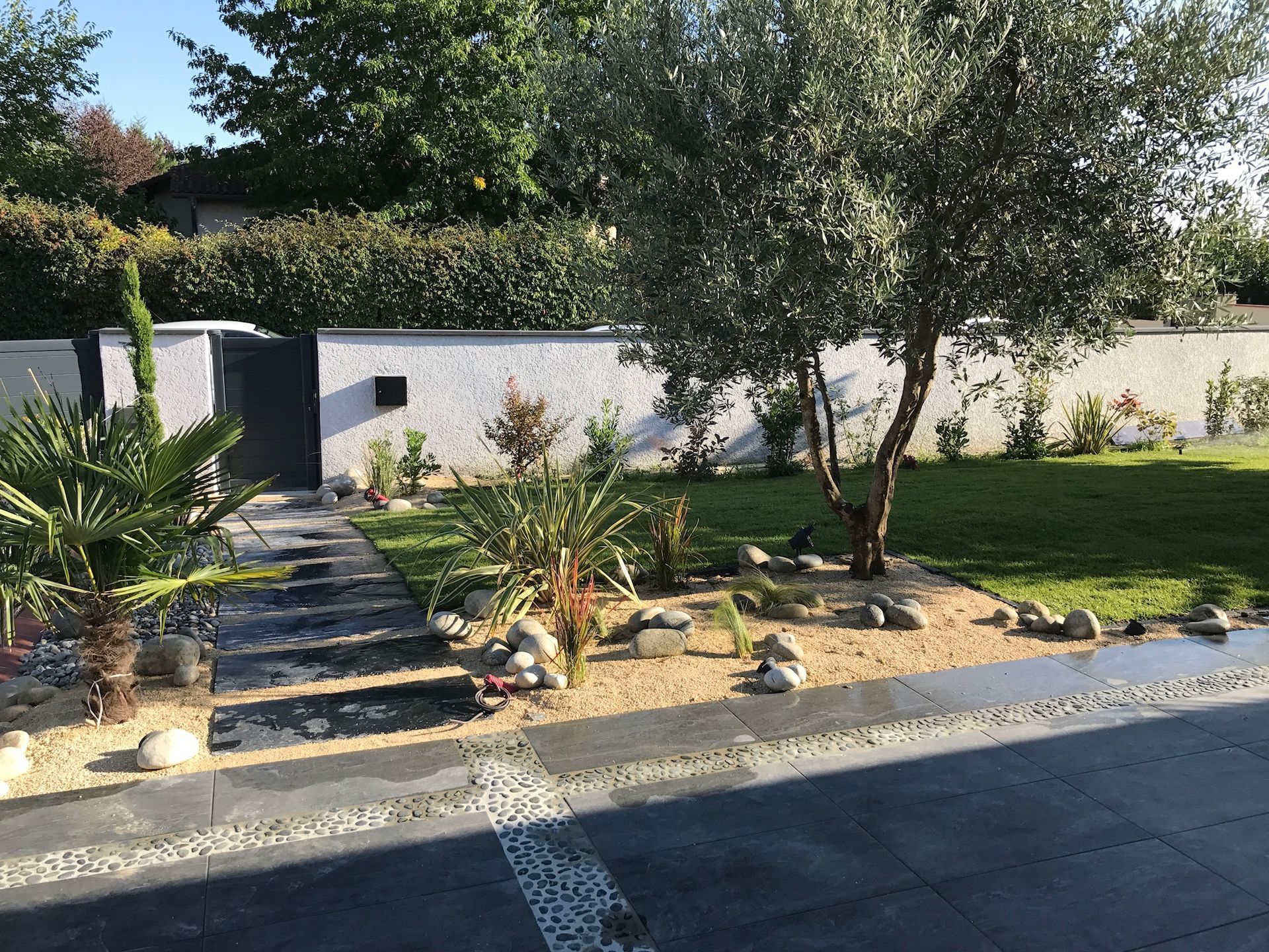 Photo d'une entrée de maison aménagée avec une allée entourée de galets et de verdure.