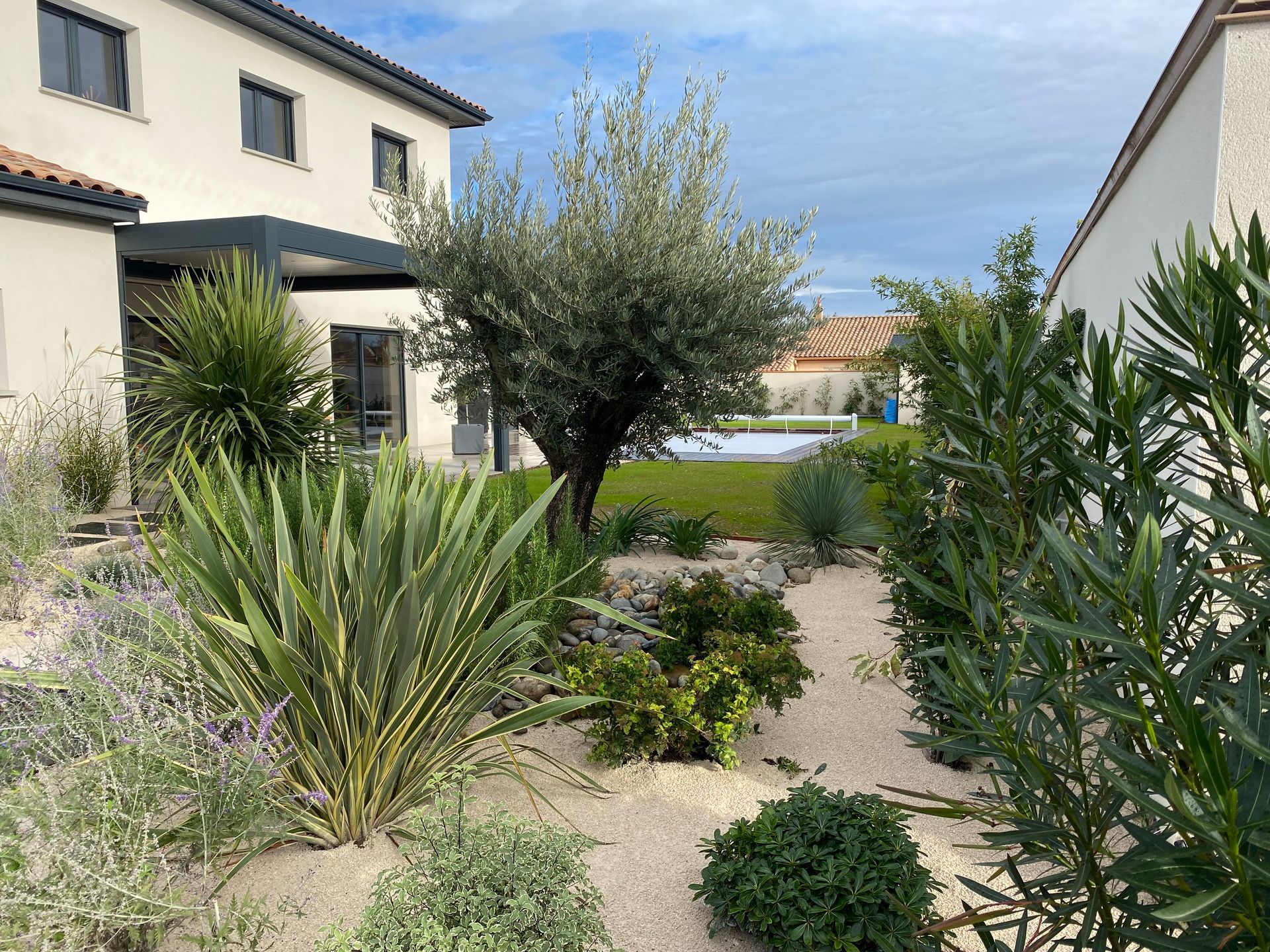 Photo d'un jardin aménagé avec une maison et une piscine en arrière plan.