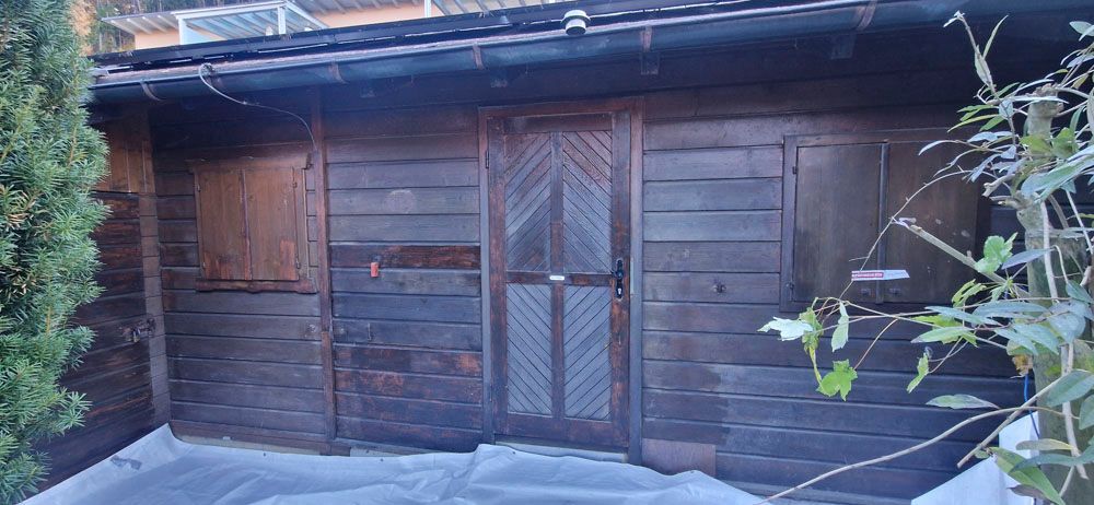 Holzschuppen mit dekorativer Tür und Fenstern.