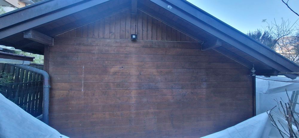 Äußeres Holzschuppen, braune Verkleidung, dunkles Dach, Schnee an den Seiten.