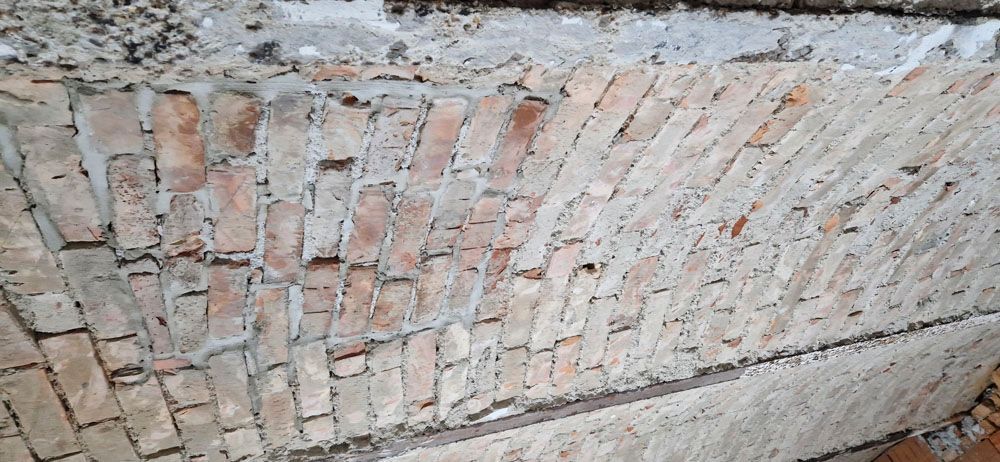 Nahaufnahme eines gemauerten Torbogens. Die Ziegel sind schräg angeordnet und in Beton eingefasst.