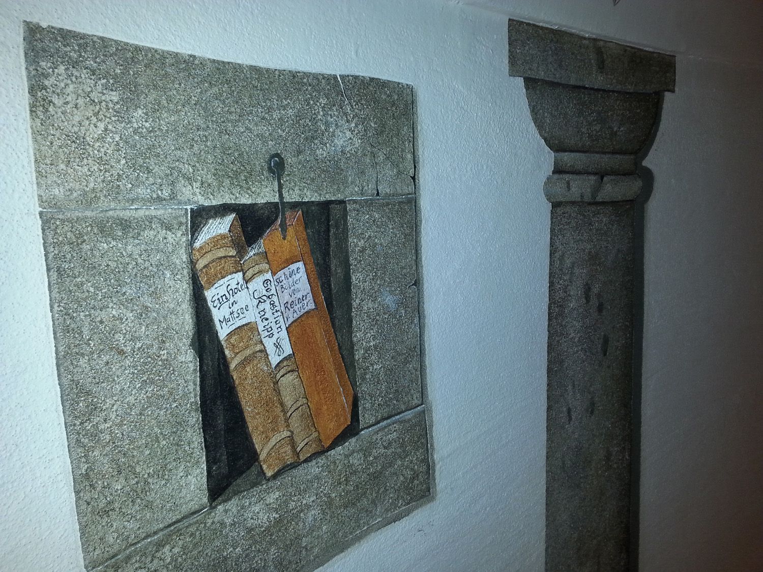 Eine Steinmauer mit einem Gemälde von Büchern darauf