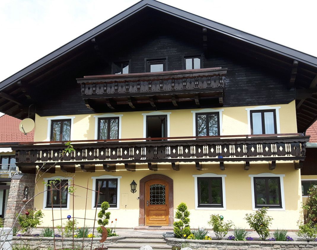 Ein gelbes Haus mit Balkon und schwarzem Dach