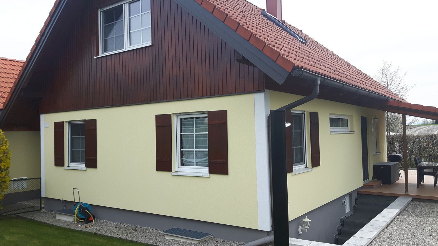 Ein gelbes Haus mit braunem Dach und Fensterläden.