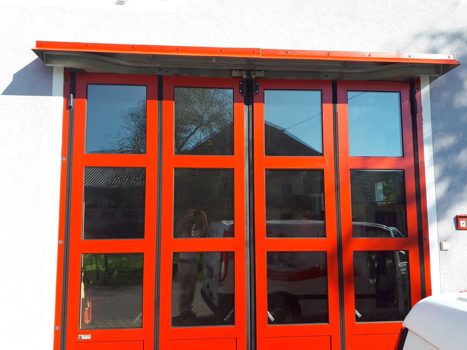 Ein rotes Garagentor mit einem davor geparkten weißen Lieferwagen