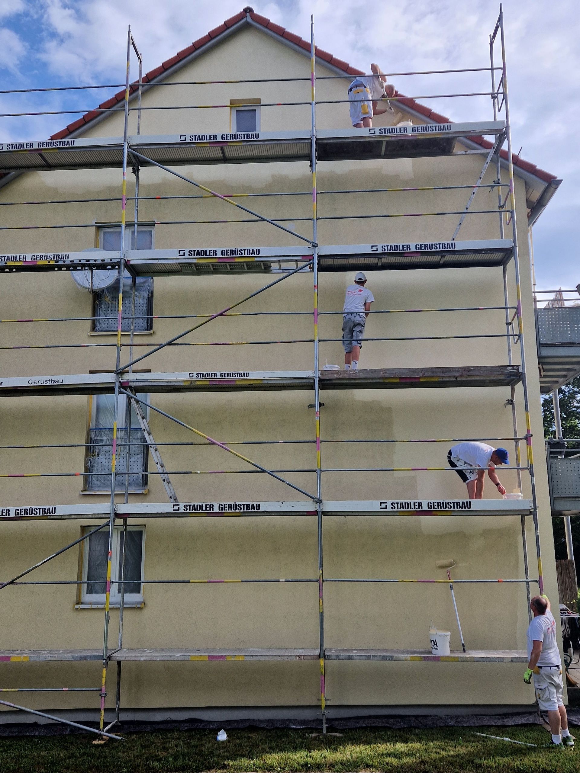 Ein Gebäude wird gestrichen, umgeben von einem Gerüst