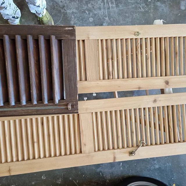 Eine Person steht neben einem Paar Fensterläden aus Holz