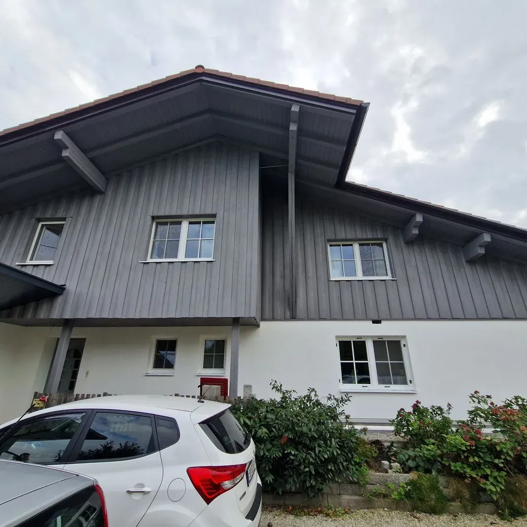 Ein weißes Auto parkt vor einem großen Haus.