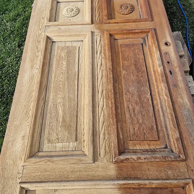 Eine Holztür liegt auf einer Holzpalette im Gras.