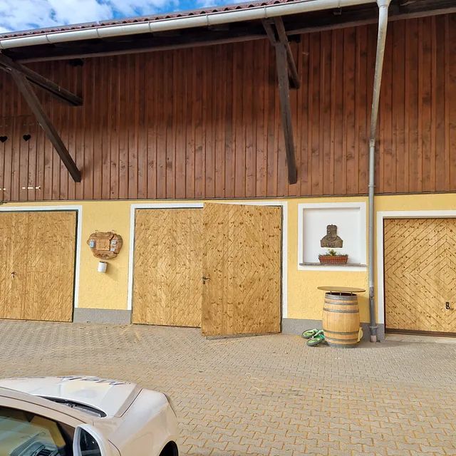 Ein weißes Auto steht vor einem Holzgebäude