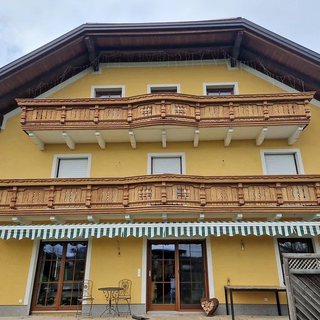 Ein gelbes Haus mit Balkon und grün-weißer Markise