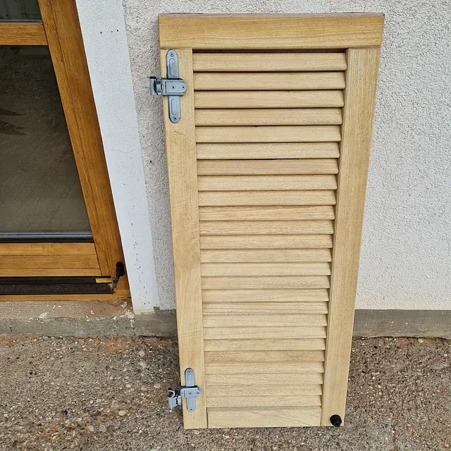 Ein Holzfensterladen sitzt vor einem Fenster
