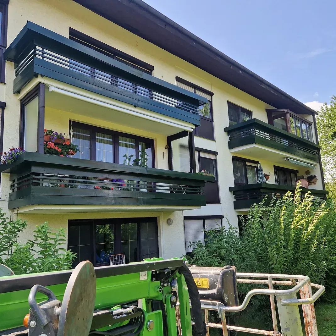 Ein grüner Traktor steht vor einem großen Gebäude.