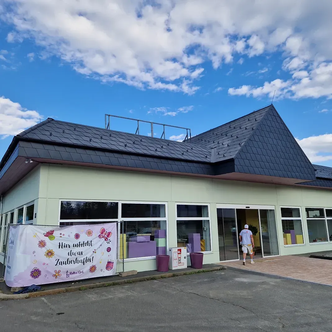 Ein grünes Gebäude mit einem blauen Dach und einem Schild mit der Aufschrift „Lila Blumen“ darauf