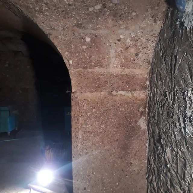 Ein Licht scheint durch einen steinernen Torbogen in einem dunklen Raum