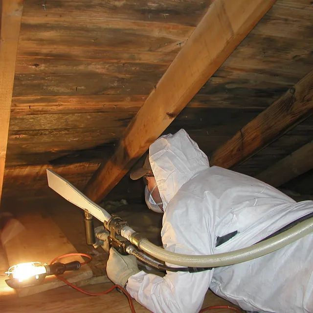 Ein Mann im weißen Anzug arbeitet unter einer Holzdecke