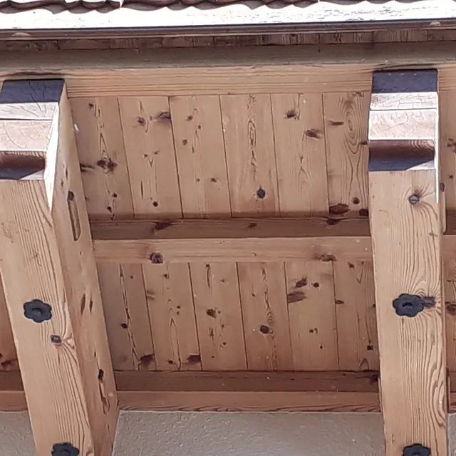 Eine Nahaufnahme einer Holzkonstruktion mit einem Dach im Hintergrund.
