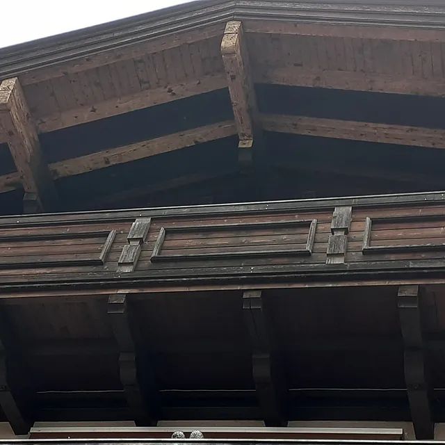 Das Dach eines Gebäudes mit Holzbalken und einem Balkon.
