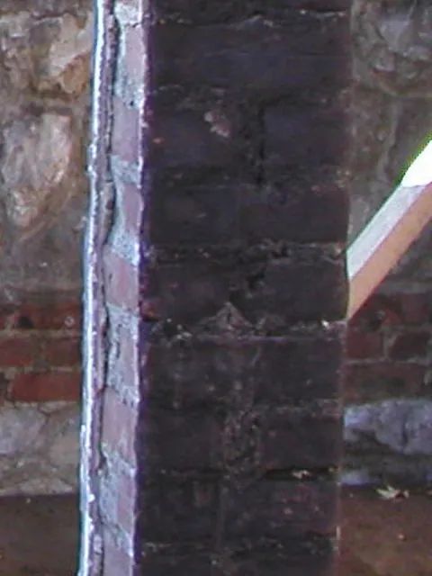 Eine Nahaufnahme einer Backsteinmauer mit einem Schornstein im Hintergrund.