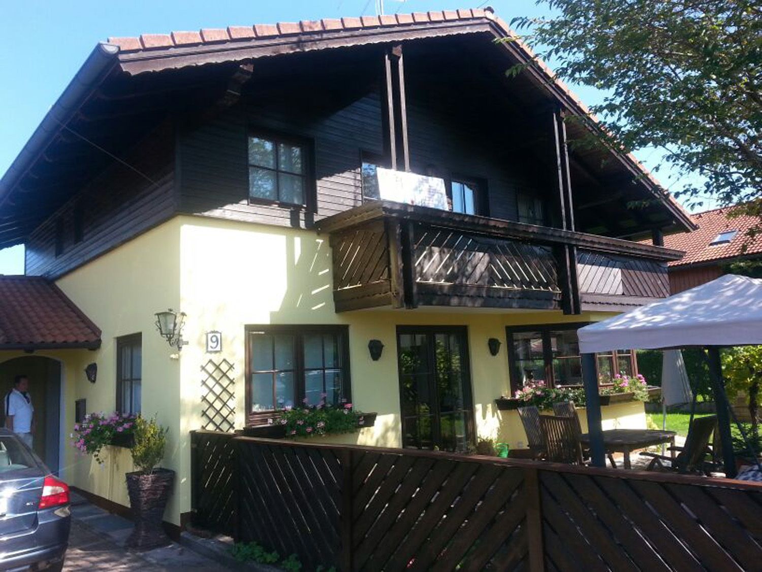 Ein gelbes Haus mit Balkon und einem davor geparkten Auto