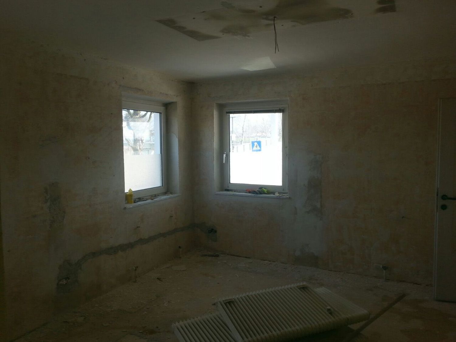 Ein leerer Raum mit zwei Fenstern und einer Tür