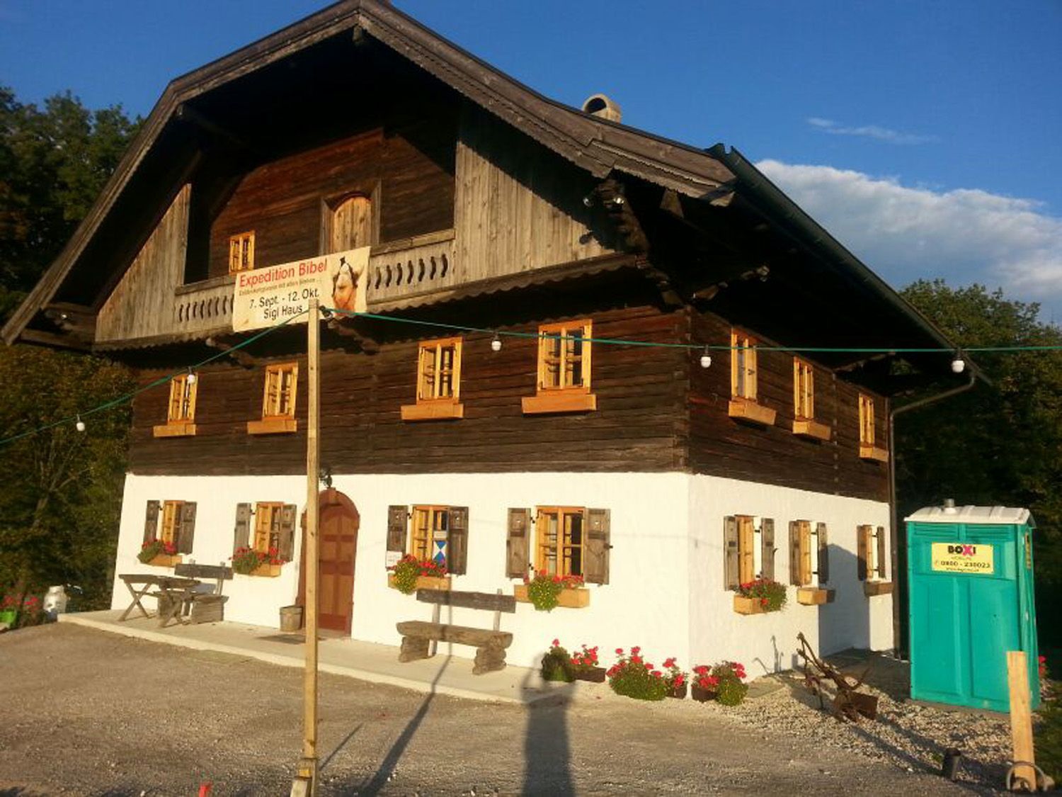 Ein großes Haus mit einer grünen Mobiltoilette davor