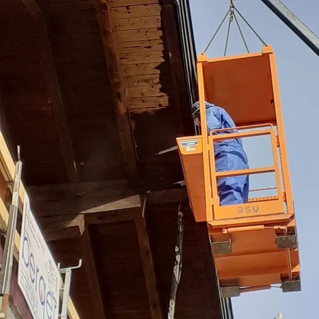 Ein Mann in einem blauen Overall sitzt in einem orangefarbenen Eimer mit der Nummer 340 darauf