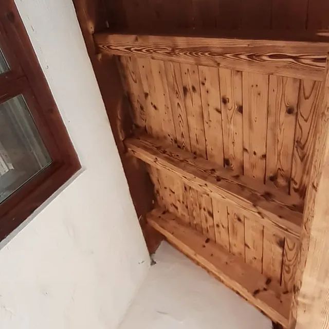 Ein Holzregal in einem Raum neben einem Fenster