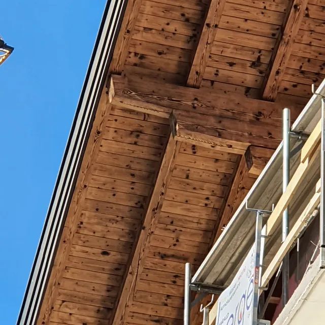 Ein Gebäude mit einem Holzdach und einem Gerüst an der Seite