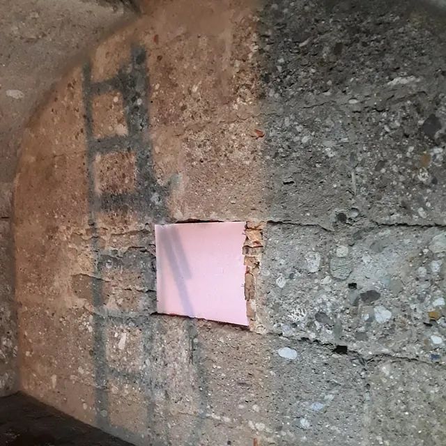 Ein Stück Papier ragt aus einem Loch in einer Betonwand.