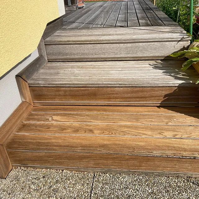 Eine Holztreppe, die zu einem Holzdeck hinaufführt.