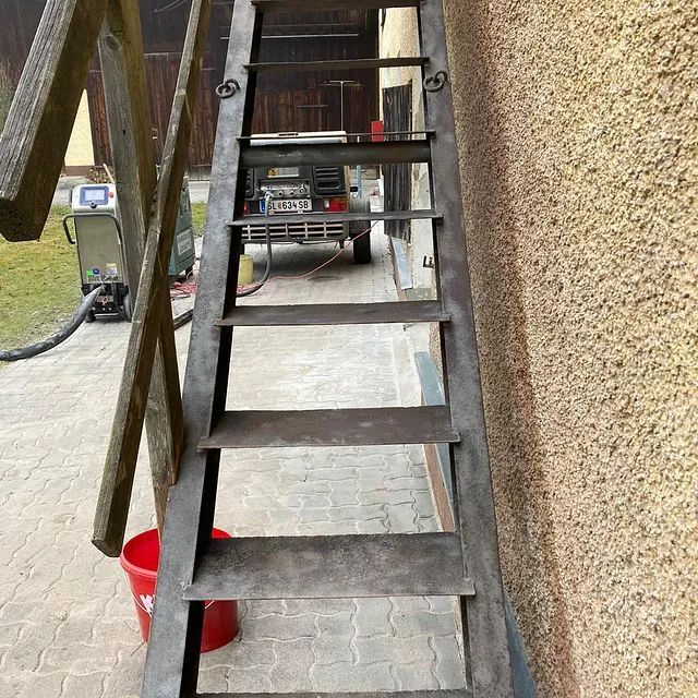 Eine Leiter mit einem roten Eimer daneben