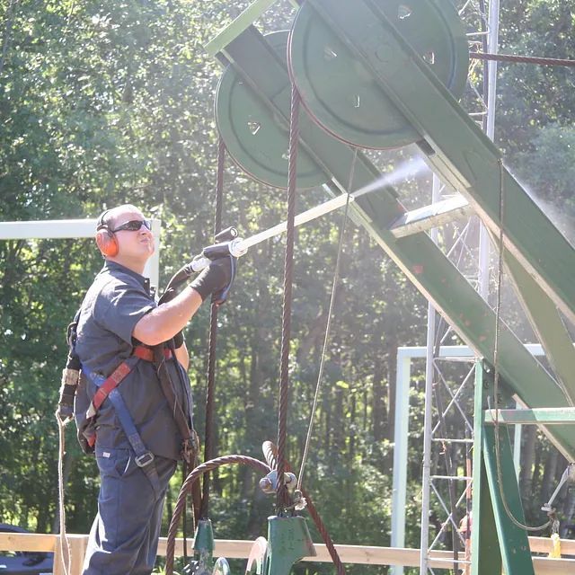 Ein Mann mit Gehörschutz besprüht einen grünen Gegenstand